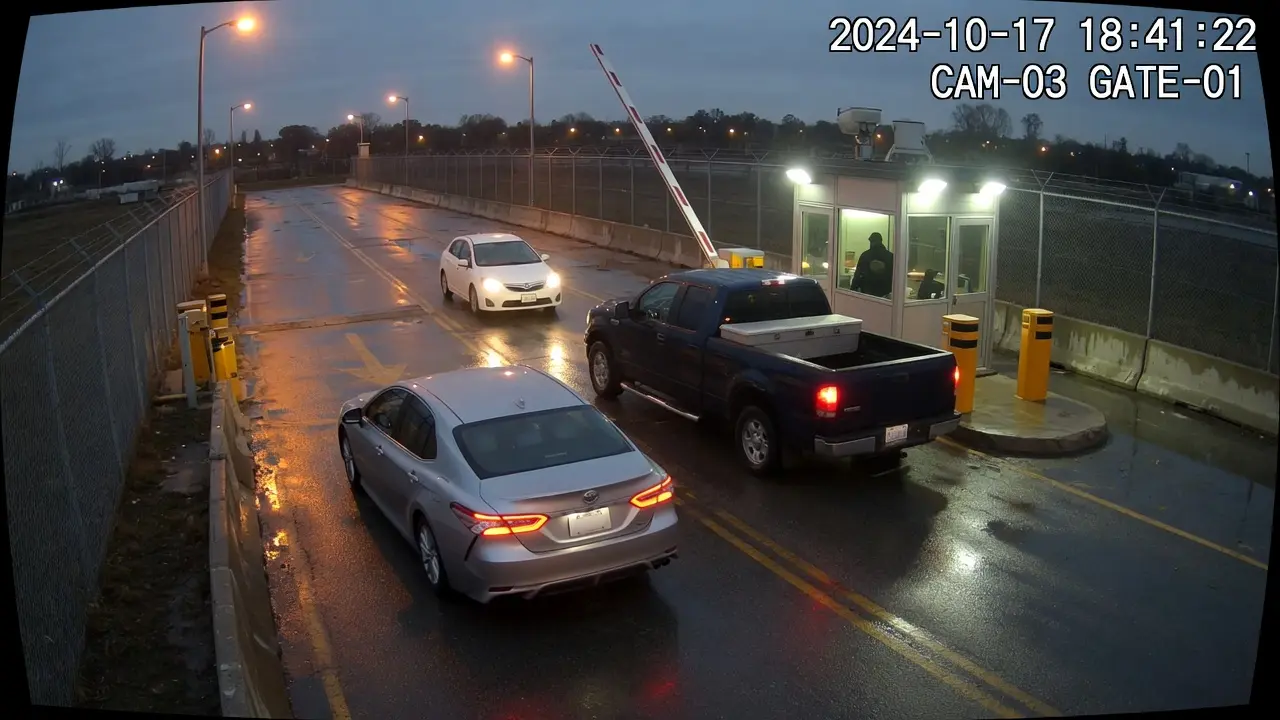 Site vehicle gate at dusk with a sedan, a pickup, and a hatchback at the barrier, AI boxes on make plate and speed