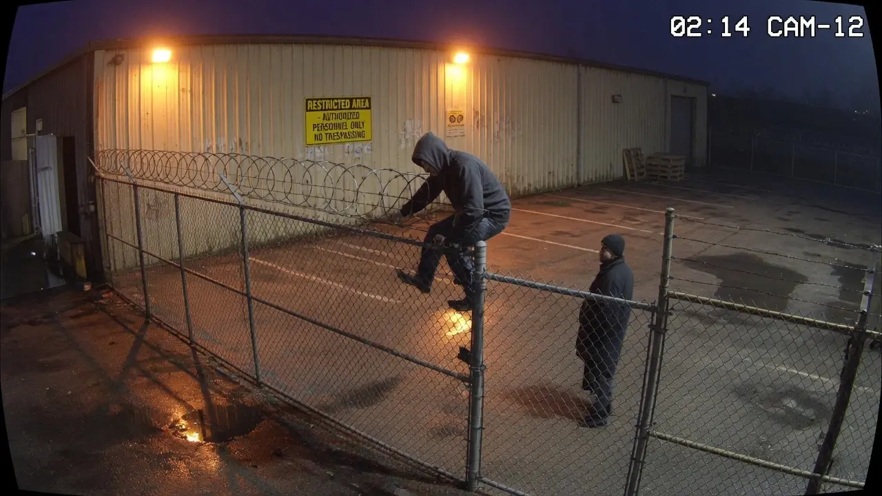 Night perimeter camera with a person climbing a chain-link fence